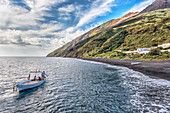 Boot mit Touristen vor Vulkanstrand von Stromboli, Äolische Inseln, Sizilien, Italien