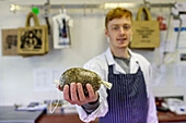 Young butcher showing haggis, Scottish national dish, Braemar, Scotland UK