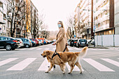 Italy, Woman with dog walking across street