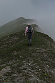 Man with backpack hiking along mountain ridge, Piedmont, Italy