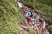 Trail runner fills up water on mountain stream. The Berlin Höhenweg trail running style - multi-day tour in the Zillertal Alps