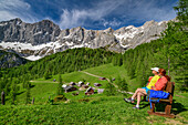 Mann und Frau beim Wandern sitzen auf Bank und blicken auf Neustattalm und Dachstein, Neustattalm, Dachstein, UNESCO Welterbe Hallstatt, Steiermark, Österreich