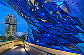 Blau beleuchtetes Gebäude der BMW Welt mit BMW Vierzylinder und BMW Museum im Hintergrund, München, Oberbayern, Bayern, Deutschland