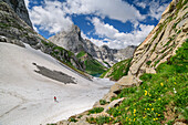 Hiking person ascends over snow field to Valentintörl, Valentintörl, Carnic Alps, Carinthia, Austria
