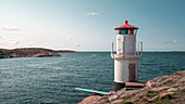 Leuchtturm und Badeplatform an der felsigen Küste von Mollösund auf der Schäreninsel Orust an der Westküste von Schweden, Sonne am Tag mit blauem Himmel\n