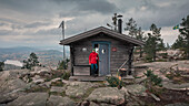 Mann verlässt Schutzhütte auf dem Gipfel des Valkallen in Höga Kusten im Osten von Schweden\n