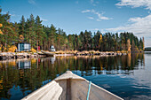 Camping mit VW Bulli Campervan am See mit Blick auf Hütte vom Boot bei Sonne in Lappland, Schweden\n