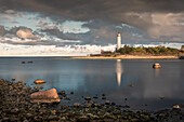Leuchtturm Lange Erik mit Reflexion im Wasser im Norden der Insel Öland im Osten von Schweden im Sonnenuntergang\n