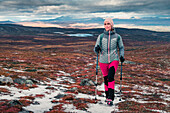 Woman hiking on Kungsleden long-distance hiking trail in Pieljekaise National Park in autumn with snow in Lapland in Sweden
