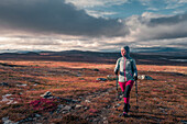 Woman hiking on Kungsleden long-distance hiking trail in Pieljekaise National Park in autumn in Lapland in Sweden