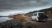 Camping mit VW Bulli Campervan in der Landschaft mit Bergen und See im Stora Sjöfallet Nationalpark im Herbst in Lappland in Schweden\n