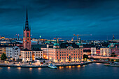 Illuminated skyline of Stockholm at night with Riddarholmskyrkan church on Gamla Stan old town island in Sweden