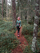 Frau wandert auf Wanderweg im Wald des Tiveden Nationalpark in Schweden\n