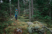 Mann wandert durch Wald mit Moos bedecktem Boden im Tyresta Nationalpark in Schweden\n