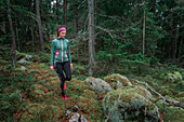Woman hiking through forest with moss covered ground in Tyresta National Park in Sweden