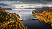 Panoramastrasse Wilderness Road mit Brücke über Fluss und Bäumen im Herbst in Lappland in Schweden von oben\n
