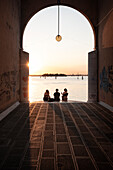 People sitting on steps at an archway at sunset, Cannaregio, Venice, Venezia, Veneto, Italy, Europe