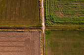 A crossing of two country lanes separates arable land and fields in Hesse, Germany