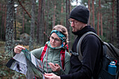 Frau und Mann lesen Wanderkarte beim Wandern im Wald im Tiveden Nationalpark in Schweden\n