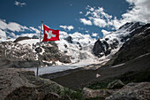 Gletscherzunge des Morteratsch Gletscher im Engadin in den Schweizer Alpen im Sommer mit Schweiz Flagge\n