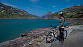 Mountain biking at the Lago Bianco reservoir at the Bernina Pass in the sun