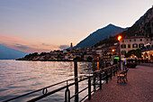 Tourists on the long lake Garda in Limone sul Garda admire the sunset. Brescia, Lombardy. Italy