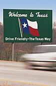 Car driving past Welcome to Texas sign at national border, Texas, USA