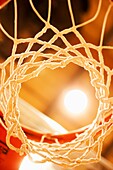 Looking up at a stadium light through a basketball net in a university gymnasium, Dallas, Texas, USA
