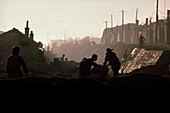 Männer arbeiten in einem Graben bei Sonnenaufgang, China