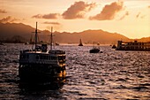Star Ferry mit Passagieren über den Victoria Harbour in der Abenddämmerung, Hongkong