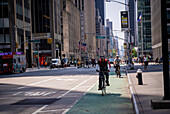 A cyclist riding down 6th Avenue in front of Radio City Music Hall and a food truck in Manhattan, New York City.