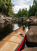 Canoe resting against rock on side of stream in wilderness