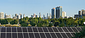 Row of solar panels with view of parkland and city in background