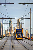 Tram travelling on lines and Surfers Paradise City in the background