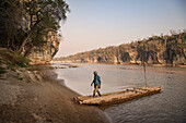 Mann steigt aus Boot am Fluss Manambolo aus, Nationalpark Tsingy de Bemaraha, Bekopaka, Madagaskar, Provinz Mahajanga, Afrika, UNESCO Weltnaturerbe
