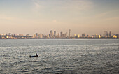 Looking across the water with lone boat to the Mumbai City skyline