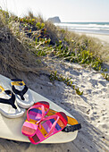Flip flops resting on surfboard in the sand