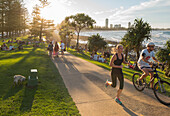 People relaxing, walking, running and cycling at Gold Coast Oceanway in late afternoon