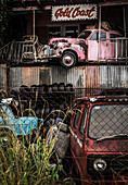 Car Wrecker Yard und rosafarbenes Gebäude mit Autowrack auf dem Balkon im Obergeschoss