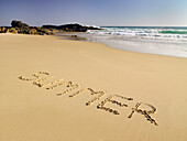The word summer written in the wet sand at the beach