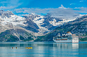 Kajakfahrer erkunden die Gewässer in Glacier Bay, während ein Kreuzfahrtschiff am Topeka-Gletscher vorbeifährt.