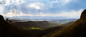 Panorama of sun rays shining on hills and valleys of Lamington National Park in late afternoon