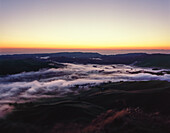 Sun rising over Hawkes Bay, New Zealand - low laying mist covering rolling green hills