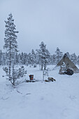 Camping teepee tent and firepit. Winter scene in Swedish Lapland