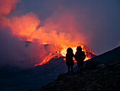 Paar genießt den Ausbruch des Vulkans Fagradalsfjall vom Beobachtungshügel aus, Island