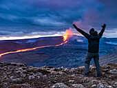 Feier, Wanderer sieht glühenden Fluss aus Magma und den Vulkanausbruch des Fagradalsfjall in Geldingadalir, Island