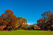 Hole 18 on Golf Course in Ascona with Autumn Trees and Clear Blue Sky in a Sunny Day with Snow-capped Mountain Peak in Ticino, Switzerland.