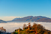 Blick auf die Berge über den Luganersee mit Wolkengebilde und Sonnenlicht und klarem Himmel in Lugano, Tessin in der Schweiz