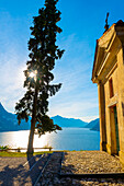 Church with Cypress Tree and Lake Lugano with Mountain and Blue Sky in Park San Michele in Castagnola in Lugano, Ticino in Switzerland.