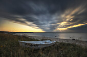 Rowing boat on Matsi Beach, Pärnu, Estonia, Baltic States, Baltic Sea. Dark clouds, sunbeams.